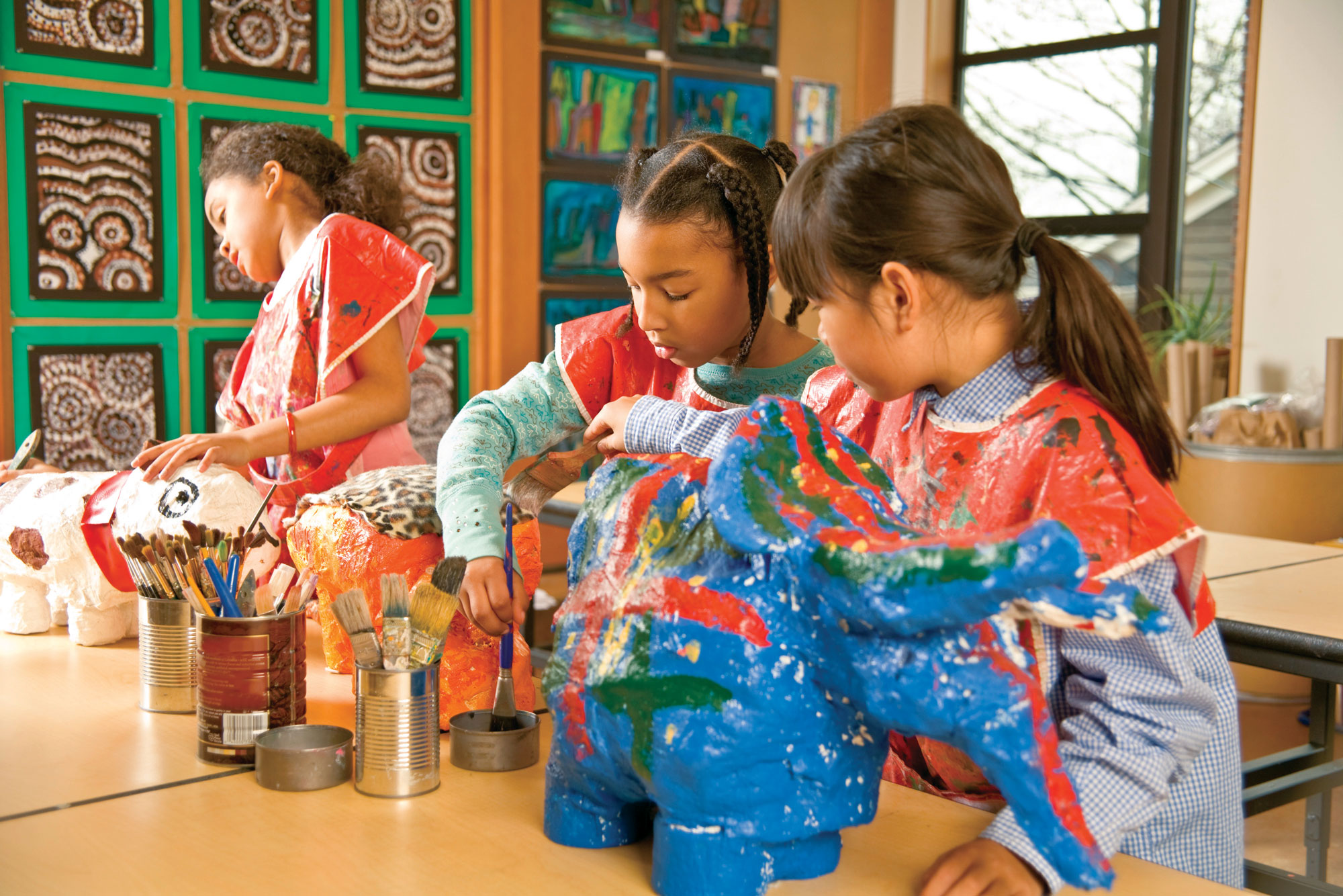 Group of children painting with coloring paints in art class.